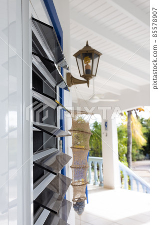 Windows from dark glass blinds. Windows in the tropics with glass blinds and mosquitos net. Selective focus. 85578907