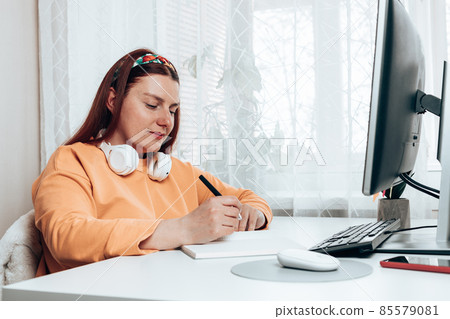 Caucasian woman student tired of learning doing homework using pc, woman studying preparing for exam test, writing in copybook doing literature research Caucasian woman student tired of learning doing homework using pc, woman studying preparing for exam test, writing in copybook doing literature research 85579081