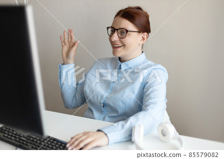 Smiling young business woman making video call on computer in office or working remotely at home. Smiling young business woman making video call on computer in office or working remotely at home. 85579082