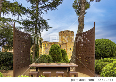 Calella de Palafrugell, Spain, a view of the Castle Tower, in the foreground a table in a steel-walled gazebo in the Botanical Garden by the sea 85579253