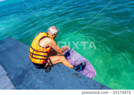 Man preparing for a wakeboard on a sea. Vacation concept, sports holidays, getaway fun with friends and family 85579478