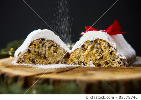 Traditional Christmas stollen made of dried fruits and nuts sprinkled with powdered sugar on the 85579746