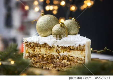 A slice of a cake on a background of christmas lights. A slice of a cake on a background of christmas lights. 85579751
