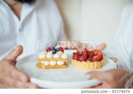 happy couple having breakfast in bed with delicious cookies with strawberries on top 85579879