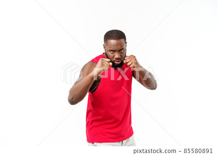 Portrait of young muscular african american male boxer looking aside, punching, standing isolated over grey background. Sport, workout, bodybuilding. 85580891