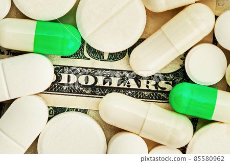 Covid-19 coronavirus pills Medicines costs dollars are scattered across the hundred dollar bills. A 85580962