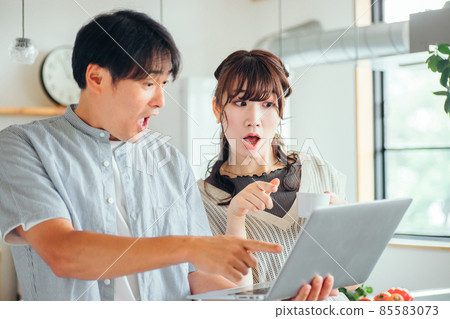 Men and women using a computer in front of the kitchen (surprise) Men and women using a computer in front of the kitchen (surprise) 85583073