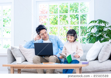 A kid sitting on the couch and working on a laptop talking to a dad at school A kid sitting on the couch and working on a laptop talking to a dad at school 85583589