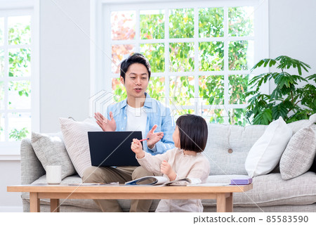 A kid sitting on the couch and working on a laptop talking to a dad at school A kid sitting on the couch and working on a laptop talking to a dad at school 85583590