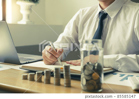 Man's is calculating financial graphs with coins to save money, grow a successful business and save for retirement. Retirement Savings concept Man's is calculating financial graphs with coins to save money, grow a successful business and save for retirement. Retirement Savings concept 85585147