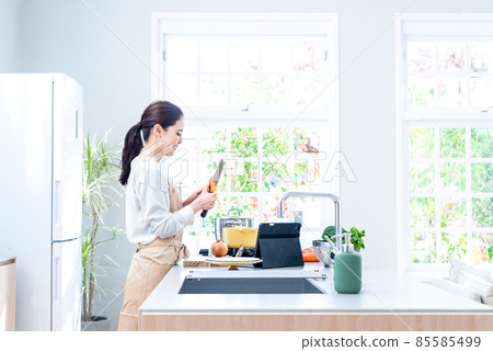 家庭主婦一邊看廚房裡的筆記本電腦視頻一邊做飯 家庭主婦一邊看廚房裡的筆記本電腦視頻一邊做飯 85585499