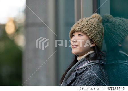 A woman leaning against the wall of a building and looking into the distance A woman leaning against the wall of a building and looking into the distance 85585542