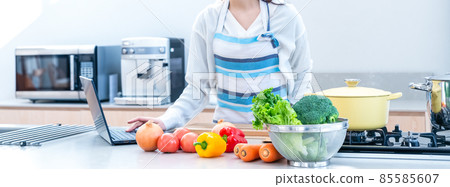 Image cut of a housewife who cooks while watching a video of a laptop computer in the kitchen Image cut of a housewife who cooks while watching a video of a laptop computer in the kitchen 85585607