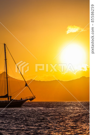 Beautiful sunset on the Aegean Sea with mountains and a sailboat. Seascape, travel and nature concept. High quality photo 85586259