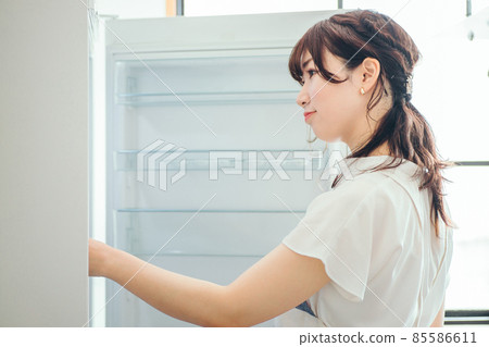 A woman looking at a fridge with nothing in it A woman looking at a fridge with nothing in it 85586611