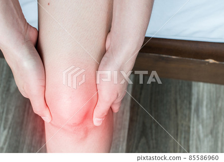 Closeup of woman hands holding and massage her knee, suffering from knee pain. Knee pain may be the result of an injury, such as a ruptured ligament or torn cartilage. Closeup of woman hands holding and massage her knee, suffering from knee pain. Knee pain may be the result of an injury, such as a ruptured ligament or torn cartilage. 85586960