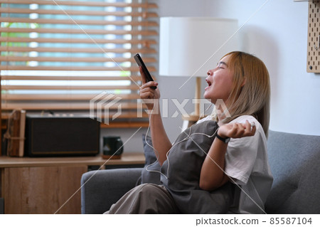Cheerful asian woman watching funny video in social network and laughing. 85587104