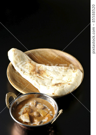 Hot massaman curry and naan with lots of ingredients such as chicken and peanuts taken on a black background Hot massaman curry and naan with lots of ingredients such as chicken and peanuts taken on a black background 85588520