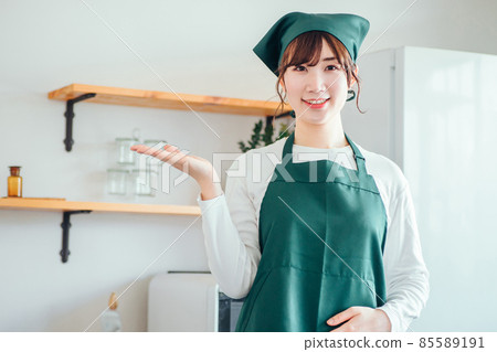 A woman in an apron standing in the kitchen 85589191