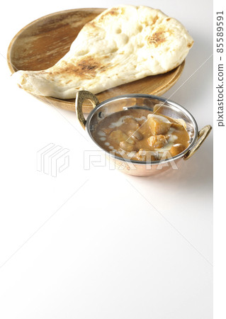 Hot massaman curry and naan with lots of ingredients such as chicken and peanuts taken on a white background Hot massaman curry and naan with lots of ingredients such as chicken and peanuts taken on a white background 85589591