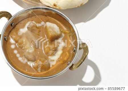 A bird's-eye view of hot massaman curry and naan containing many ingredients such as chicken and peanuts on a white background 85589677