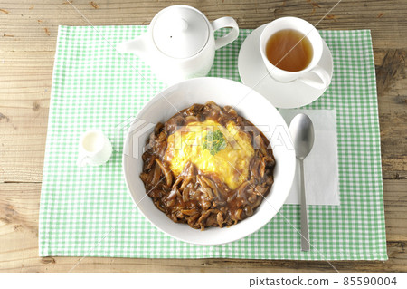 A bird's-eye view of hot omelet rice with plenty of hayashi sauce, a teapot, a milk pitcher, and tea. A bird's-eye view of hot omelet rice with plenty of hayashi sauce, a teapot, a milk pitcher, and tea. 85590004