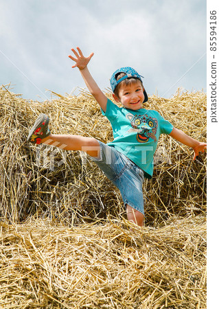 Schoolboy boy jumping and having fun on straw bales on summer day 85594186