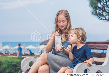 Mom and son eat fried sweet potatoes in the park. Junk food concept 85594252