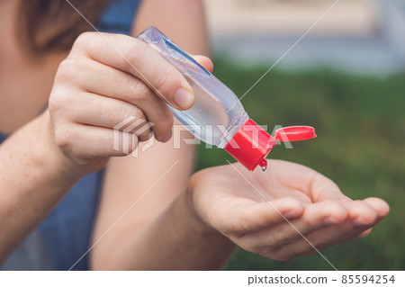 Women's hands using wash hand sanitizer gel pump dispenser Women's hands using wash hand sanitizer gel pump dispenser 85594254