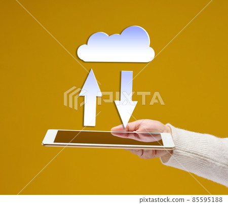 female hand holds an electronic gadget tablet on a yellow background, white cloud with arrows above it. Information exchange, data warehouse. Uploading a backup female hand holds an electronic gadget tablet on a yellow background, white cloud with arrows above it. Information exchange, data warehouse. Uploading a backup 85595188