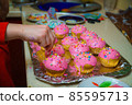 Freshly baked vanilla muffins are garnished with sweet icing and topping. 85595713