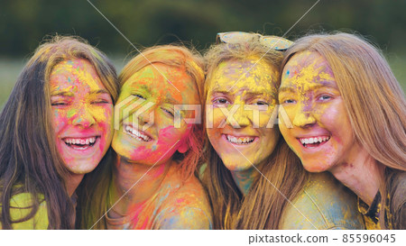 Cheerful girls posing smeared in multi-colored powder. Cheerful girls posing smeared in multi-colored powder. 85596045
