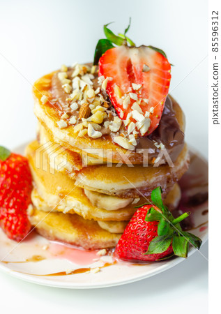 Pancakes stacked with bananas, strawberries and nuts, topped with chocolate and strawberry sauce Pancakes stacked with bananas, strawberries and nuts, topped with chocolate and strawberry sauce 85596312