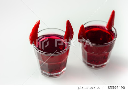 Drink shot prepared with vodka, grenadine and lemon juice decorated with bird eye chillies in the shape of horns Drink shot prepared with vodka, grenadine and lemon juice decorated with bird eye chillies in the shape of horns 85596490