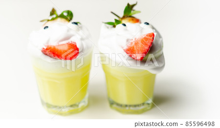 Egg liqueur in shot glass decorated with fluffy whipped cream and pieces of strawberry, served in funny way Egg liqueur in shot glass decorated with fluffy whipped cream and pieces of strawberry, served in funny way 85596498