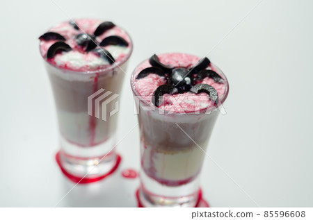 Drinks shots prepared by the bartender at the Halloween party decorated with black olives in the shape of spiders 85596608