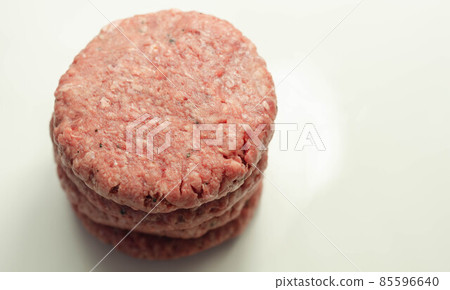Raw beef burgers with a pinch of salt and black pepper on the white background Raw beef burgers with a pinch of salt and black pepper on the white background 85596640