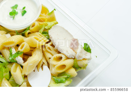 Penne pasta in a mayonnaise dressing with bacon pieces topped with parsley rubbed cooked chicken breast pieces 85596658