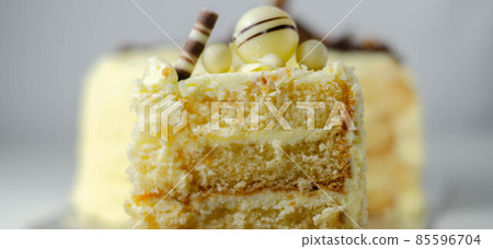 A piece of layered white cream cake with confectionery decorations A piece of layered white cream cake with confectionery decorations 85596704