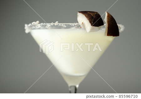Coconut cocktail in martini glass based on the rum decorated with coconut flakes and coconut pieces 85596710