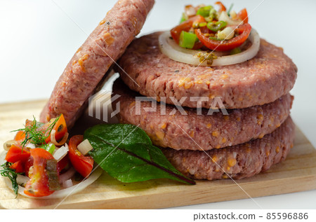 Raw beef burgers blended with caramelised red onion and tangy red Leicester cheese prepared for grilling Raw beef burgers blended with caramelised red onion and tangy red Leicester cheese prepared for grilling 85596886