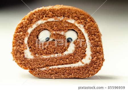 Chocolate sponge roll with a vanilla flavour filling with decorating sweet eyes, chocolate swiss roll 85596939