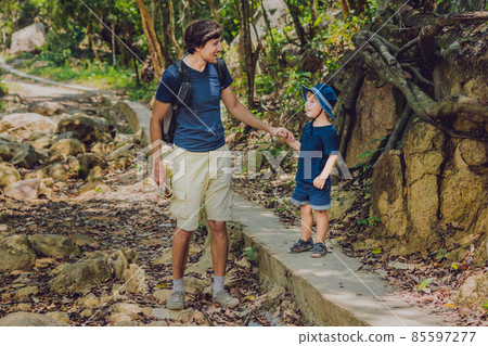 Father and son are walking along the forest road Father and son are walking along the forest road 85597277