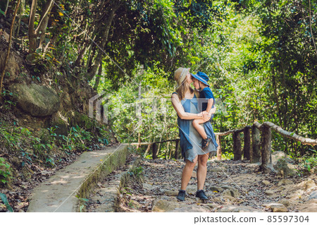 Mom and son are walking on the forest road Mom and son are walking on the forest road 85597304