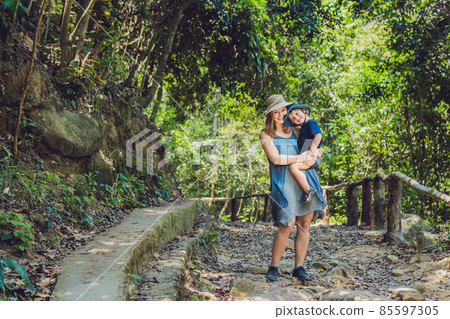 Mom and son are walking on the forest road Mom and son are walking on the forest road 85597305