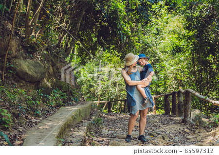 Mom and son are standing on the forest road 85597312