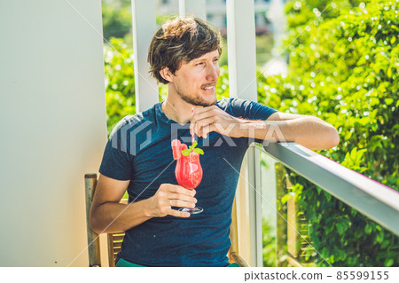 Man is holding Healthy watermelon smoothie with mint and striped straws on a wood background 85599155