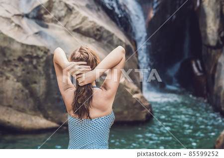 Young woman sits on a waterfall background 85599252