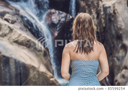 Young woman sits on a waterfall background 85599254