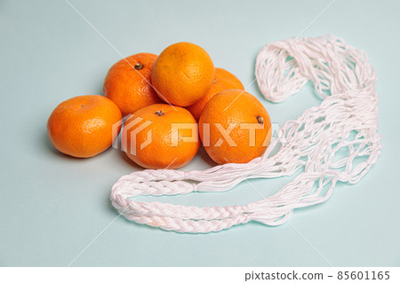 Eco-friendly mesh with tangerines on a blue background. Eco-friendly mesh with tangerines on a blue background. 85601165